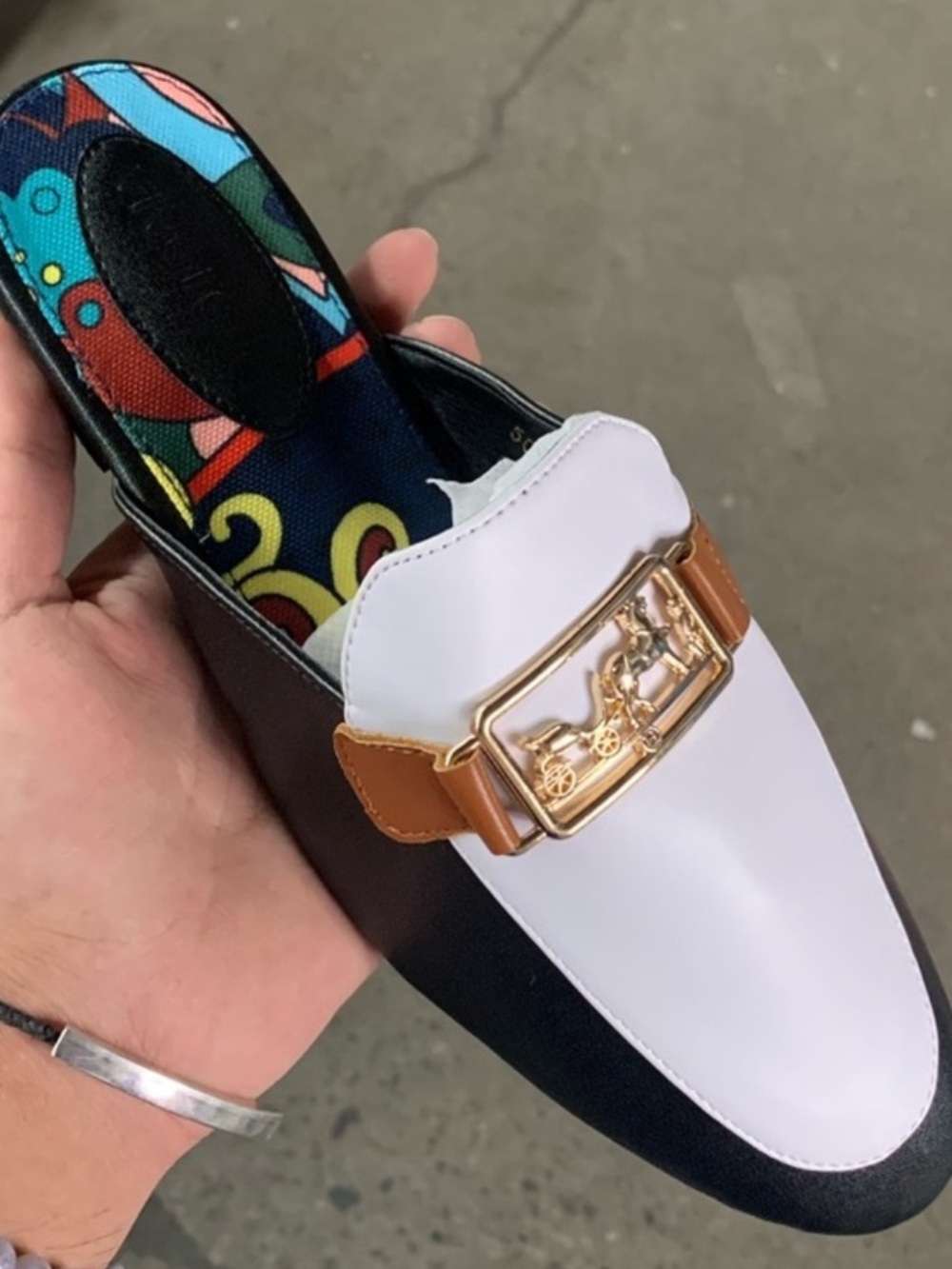 Women’s white and black loafers with gold detail.